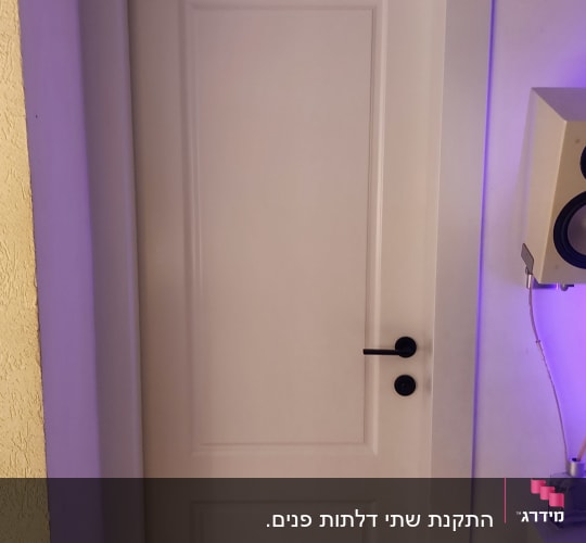 דלת לבנה עם ידית שחורה על רקע קיר סגול